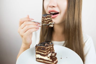 young beautiful girl eating cake, close-up, crop photo.
