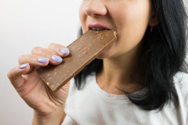 Çikolata yiyen bir kadının yakın çekimi. Kesilmiş fotoğraf.