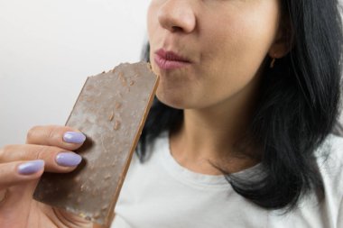 Çikolata yiyen bir kadının yakın çekimi. Kesilmiş fotoğraf.