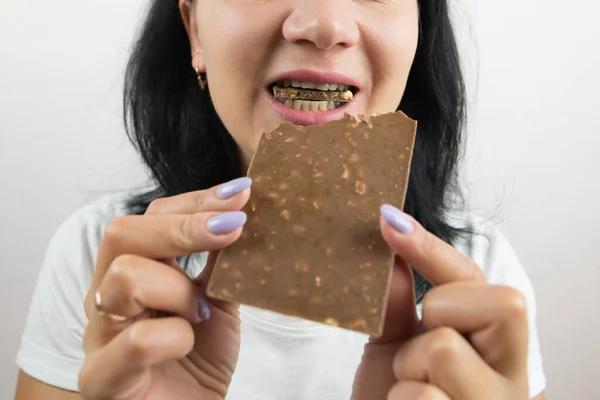 Close-up of a woman eating a chocolate bar. Cropped photo.