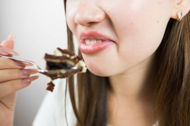 young beautiful girl eating cake, close-up, crop photo.