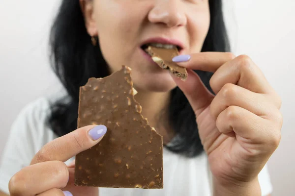 Close-up of a woman eating a chocolate bar. Cropped photo.