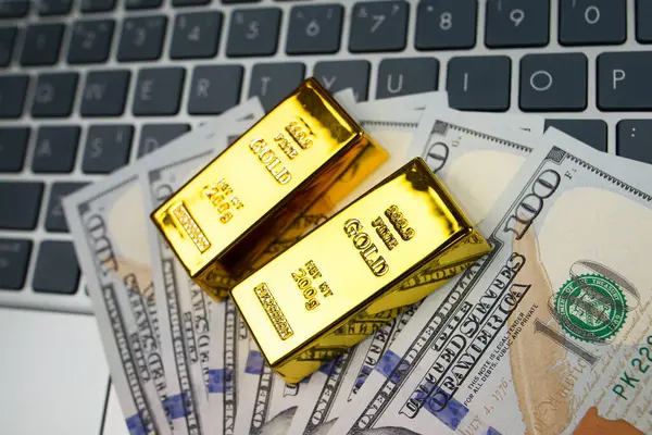 Gold bars notebook and dollars on white.Concept of gold futures trading, online asset trading or buying gold bars for investment.
