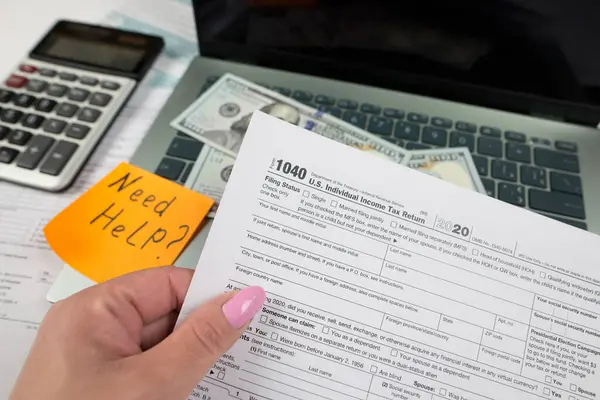 Tax day concept. Hand holding of form 1040. U.S. individual income tax return while sitting at the table in the office. Close-up photo