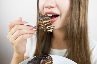 young beautiful girl eating cake, close-up, crop photo.