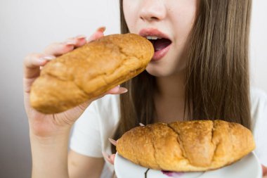 young beautiful girl eating a croissant, close-up, crop photo.