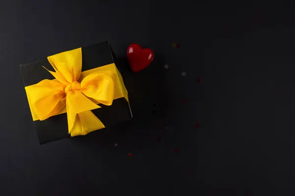 Top View Photo Gift Box Yellow Bow Heart Black Background — Stock Photo, Image