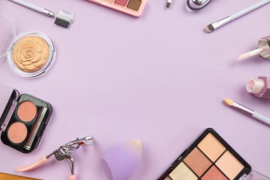 Makyaj konsepti. Üst görüntü fotoğrafı. Profesyonel dekoratif kozmetik seti, makyaj araçları ve aksesuarlar fotokopi alanı olan bir pastel mor arkaplan üzerinde