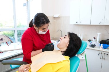 Diş hekimi hastaya diş kaplaması yapar. Kurulum süreci. Diş hekimliği, gülümseme tasarımı, beyaz dişler. Dişlerin restorasyonu..