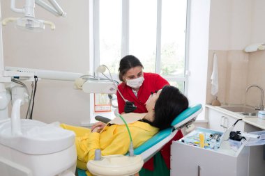 Diş hekimi hastaya diş kaplaması yapar. Kurulum süreci. Diş hekimliği, gülümseme tasarımı, beyaz dişler. Dişlerin restorasyonu..