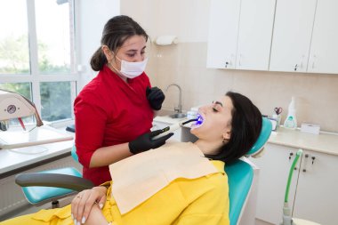 Diş hekimi hastaya diş kaplaması yapar. Kurulum süreci. Diş hekimliği, gülümseme tasarımı, beyaz dişler. Dişlerin restorasyonu..