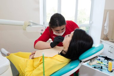 Diş hekimi hastaya diş kaplaması yapar. Kurulum süreci. Diş hekimliği, gülümseme tasarımı, beyaz dişler. Dişlerin restorasyonu..