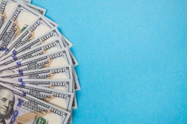 İzole edilmiş mavi arka planda 100 dolarlık banknotları kapat.