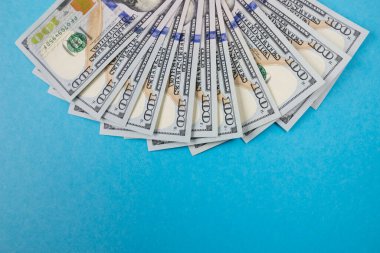 İzole edilmiş mavi arka planda 100 dolarlık banknotları kapat.