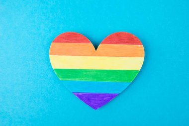 Mavi arkaplanda LGBT sembolünün bir kalbinin fotoğrafı, birinci kişinin üst görünümü.