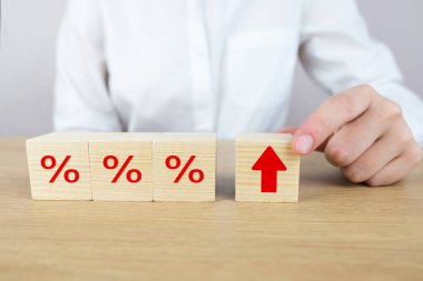 Faiz oranı finansal ve ipotek oranları kavramı. Elle yerleştirilen tahta kübü, simge yüzdesi sembolü ve ok yönüyle yukarı doğru artar