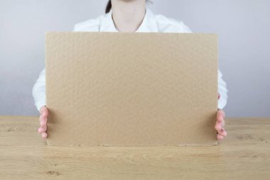 Elinde boş karton çarşaf, tebrik kartı taşıyan bir kadın. Elinde boş ilan panosu tutan bir kadın.