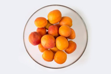 beyaz zemin üzerinde bir cam kasede olgun kayısı