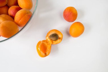 beyaz zemin üzerinde bir cam kasede olgun kayısı