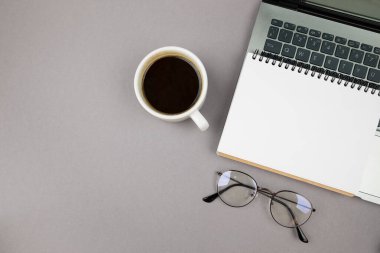 Gri arka planda dizüstü bilgisayar kahvesi ve bardaklar.