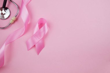Top view photo of pink ribbon symbol of breast cancer awareness and stethoscope on isolated pastel pink background with copyspace