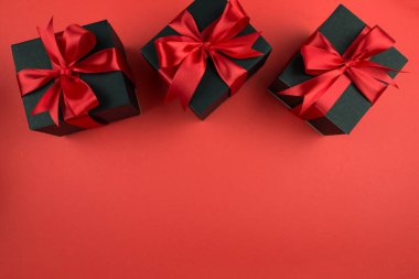 İzole edilmiş kırmızı arka planda fiyonklu hediye kutularının üst görünümü.