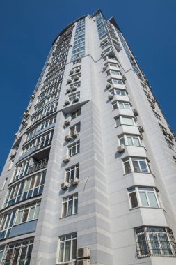 Mavi gökyüzü arka planında balkonları olan çok katlı bir bina..