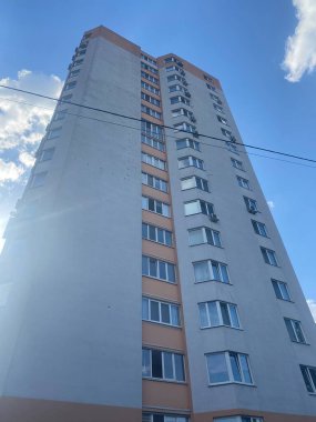 Mavi gökyüzü arka planında balkonları olan çok katlı bir bina..