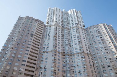 Mavi gökyüzü arka planında balkonları olan çok katlı bir bina..