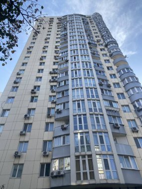 Mavi gökyüzü arka planında balkonları olan çok katlı bir bina..