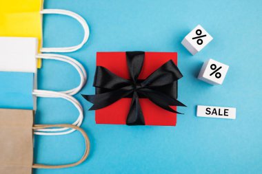 Hediye kutusu ve mavi arka planda alışveriş torbaları. Kara Cuma satışları. Pankart.