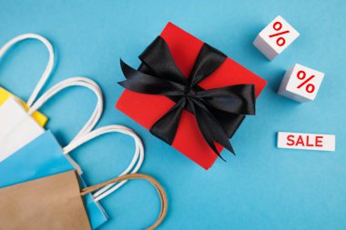 Hediye kutusu ve mavi arka planda alışveriş torbaları. Kara Cuma satışları. Pankart.