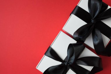 Kırmızı arkaplanda siyah saten kurdeleli iki kutu kopyalama alanı