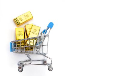 Beyaz arka planda alışveriş arabasındaki altın külçeler.