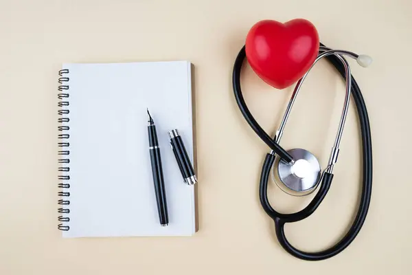 Stetoskop, kırmızı kalp ve arka planda not defteri, üst manzara. Kardiyoloji ve sağlık konsepti. Tıbbi bakım.
