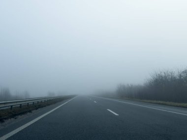 Yoğun bir siste, bomboş bir asfalt yolu (karayolu). Yaya geçidi, kavşak, sokak lambaları. Tehlikeli sürüş, yürüyüş, bisiklet, trafik kanunları