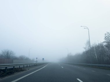 Yoğun bir siste, bomboş bir asfalt yolu (karayolu). Yaya geçidi, kavşak, sokak lambaları. Tehlikeli sürüş, yürüyüş, bisiklet, trafik kanunları