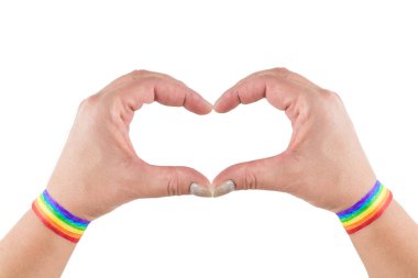 Kalp şeklinde genç bir kadının elleri. LGBT, eşcinsel aşk ve homoseksüel ilişkiler kavramı. Gökkuşağı bilezikli kadın ellerine yakın çekim. 