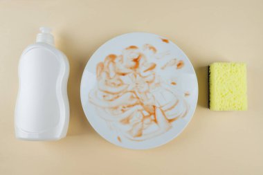 Kirli beyaz tabak şişesi, bej arka planda bulaşık deterjanı. Bulaşıkları yıka.