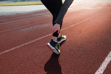 Atletik bayan koşucunun ayak bileği burkulduğu için bacağına dokunduğu fotoğraf, arka görüş. Koşu sporu, eğitim sakatlığı