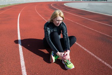 Ayağında ağrı olan bir kızın fotoğrafı. Stadyumda antrenman sırasında yaralanmış. Arka görüş, bacak ağrısı, kas gerginliği.