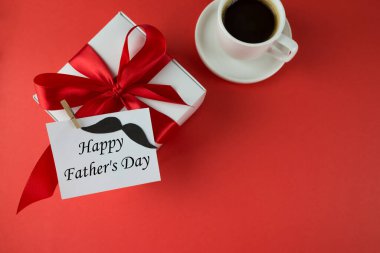 Babalar Günün kutlu olsun. Kırmızı fiyonklu hediye kutusu ve kırmızı arka planda aksesuarlar. Kart, pankart, Babalar Günü için plan. Kırmızı gölgeler.