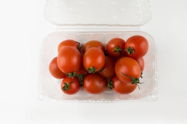 Beyaz arka planda plastik bir kabın içindeki domatesler
