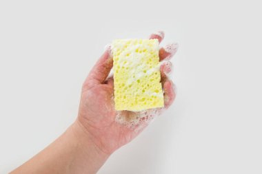 Beyaz arka planda el ele tutuşan temizlik süngeri. Elde bulaşık yıkamak için bir sünger.