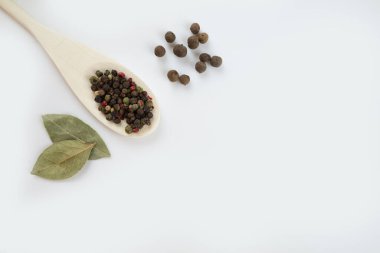 Koy yaprağı aromatik biber ve biber karışımı beyaz arka planda tahta kaşık, boşluğu kopyala.
