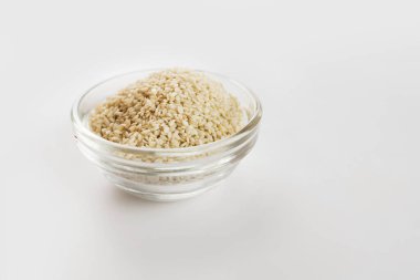 Beyaz arka planda cam bir kasede susam.