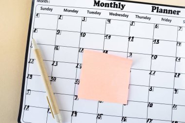 Takvim. Yapışkan notlu takvim sayfası, bej arkaplanlı kalem, üst görünüm. Mesaj için yer var. Planlayıcı.