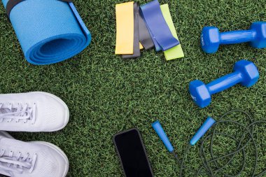 Yeşil çim arka planda fitness ekipmanları. Spor malzemeleri, çimlerin üzerinde spor aksesuarları. Spor anlayışı, spor anlayışı, sağlıklı yaşam tarzı.