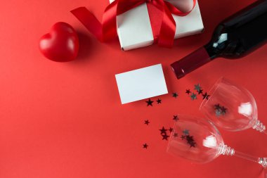 Kırmızı arka planda şarap şişesi ve hediye kutusu, 14 Şubat konsepti.