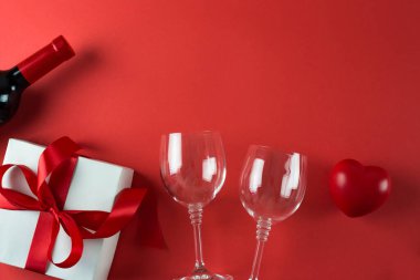 Kırmızı arka planda şarap şişesi ve hediye kutusu, 14 Şubat konsepti.